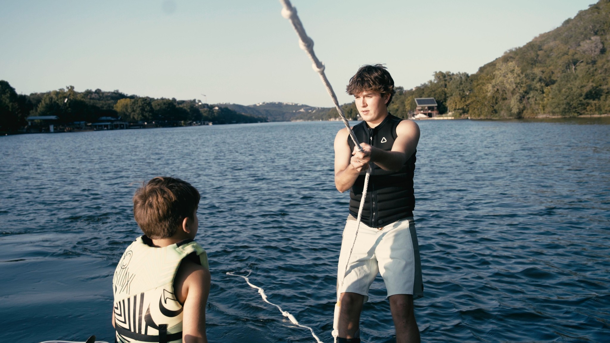 Wake surf instructor teaching student on the dock at Lake Austin, wakesurf board visible